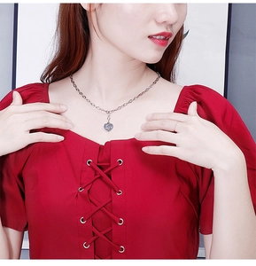 Detail of silver heart pendant engraved with Love on a red square neck dress