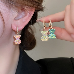 Détail macro de boucles d'oreilles ours en résine colorée avec pendentifs cerceaux dorés