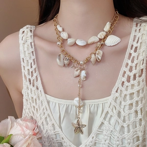 Detail of layered gold necklace with natural shells, pearls and starfish pendant on model