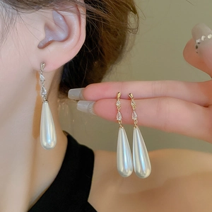 Detail of waterdrop pearl earrings with sparkling zircon accents on gold plating