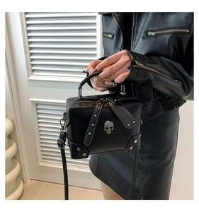 Detail of black punk square bag with silver skull motif and metal studs on PU leather