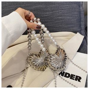 Macro detail of heart-shaped silver metal bag with shell texture and pearl strap
