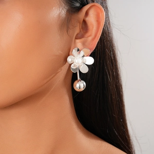Close-up of elegant flower stud earring with white pearl and hanging metal sphere