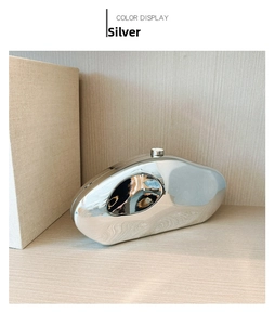 Detail of silver metallic pebble clutch with organic curves and modern cylindrical clasp