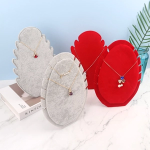 Gray and red velvet flame-shaped necklace display stands set on marble surface