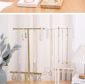 Detailed close-up of a double-layer metal jewelry stand with solid wood base on a desk