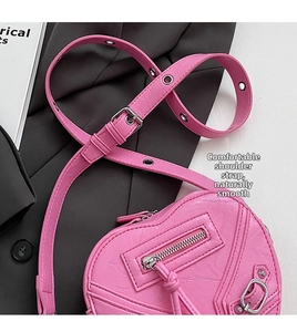 Détail du sac coeur rose avec rivets argentés et bandoulière à œillets réglable
