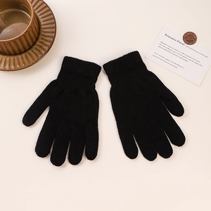 Detail of warm black knitted gloves on a cozy desk with a coffee cup and card