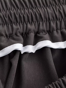 Close-up of dark grey elastic waistband with white piping and fine plain weave texture