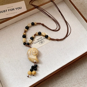 Dettaglio del ciondolo a spirale su una collana di perline vintage in stile etnico
