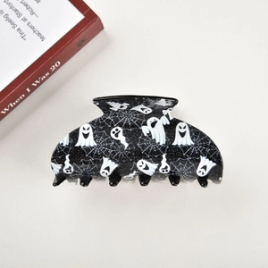 Detailed top view of a black Halloween hair claw clip with white ghost and spider web patterns
