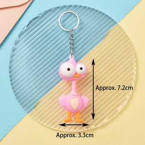 Pink cartoon bird keychain with large eyes and orange beak on a colorful background