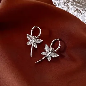 Silver dragonfly earrings with marquise zircon stones and hoops on brown velvet
