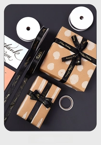 Macro detail of black fabric ribbon with gold Happy Birthday foil print for gift wrapping