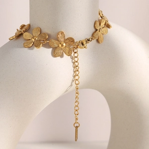 Macro detail of 18K gold plated daisy flower link bracelet with brushed metal texture