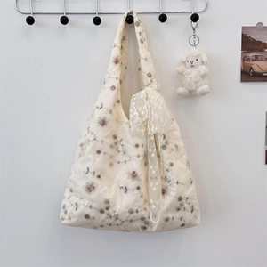 Close-up of floral embroidery and large bow detail on a beige tote shoulder bag