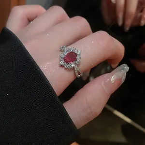 Elegant silver open ring featuring an oval red zircon center stone and halo of white gems