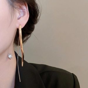 Elegant gold drop earrings with wavy minimalist lines on model in black blazer