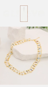 Detail of double-strand pearl necklace with multi-color beads on a white stone base