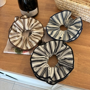 Three large striped fabric scrunchies in brown blue and black on a wooden table