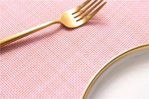 Detailed texture of pink woven placemat with golden fork and elegant white plate
