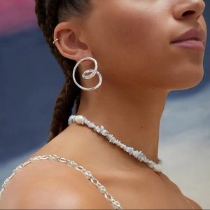 Minimalist silver swirl drop earrings and gemstone necklace set on elegant model