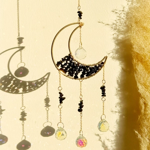 Detail of moon suncatcher with black crystals and rainbow light reflections on the wall