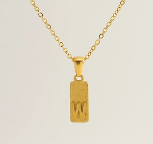 Macro view of gold-plated square pendant with frosted texture and engraved letter W
