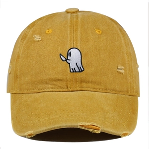 Detailed close-up of cute ghost embroidery and distressed holes on yellow cotton baseball cap