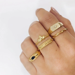 Ensemble de bagues géométriques en or 18 carats avec émail portées par un mannequin main
