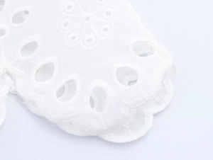 Close-up of white cotton lace embroidery with hollow geometric floral patterns