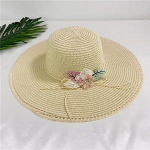Close-up of wide brim straw hat with crochet lace edge and fabric flower detail