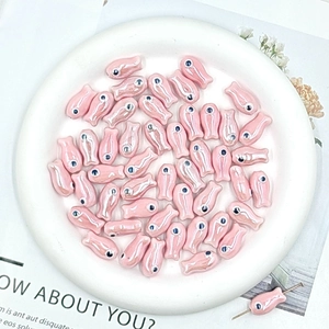 Macro shot of small pink ceramic fish beads for DIY jewelry making and crafting