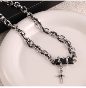 Detailed macro view of silver and black layered necklace with rectangle and cross charms