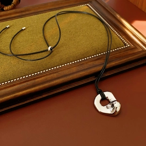Detail of silver irregular metal pendant on black cord necklace with mirror finish