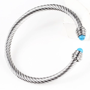 Detail of twisted cable cuff bracelet in silver stainless steel with blue stone ends