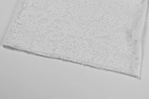 Detail of delicate white lace fabric featuring floral embroidery for elegant women's dress