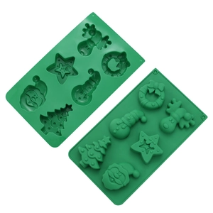 Macro detail of green silicone Christmas molds featuring Santa, trees, and snowmen motifs