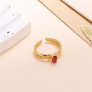 Detailed close-up of a gold adjustable ring with a red oval gemstone and twisted band