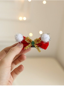 Détail d'une pince à cheveux de Noël en velours rouge avec liseréger liseré doré et pompon