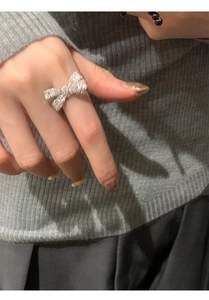 Macro detail of silver bow ring encrusted with zircon crystals on woman's finger