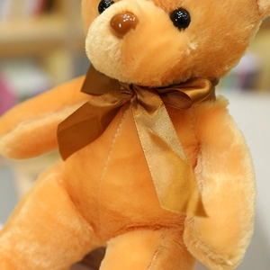 Detalle de cerca de un suave oso de peluche naranja con un lazo de cinta de raso marrón.