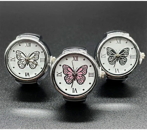 Close-up of three silver ring watches featuring white dials with butterfly motifs