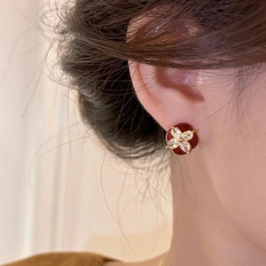 Close-up of vintage gold floral stud earrings with red oil-drip base and zircon petals