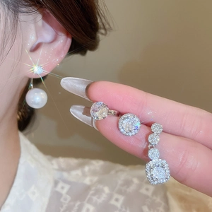 Macro shot of silver stud earrings with sparkling zircons and a white pearl drop