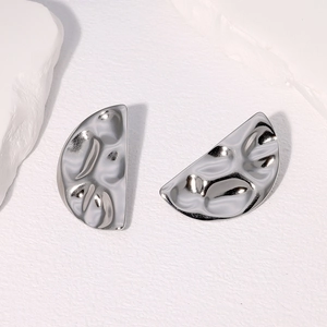 Macro shot of silver geometric semi-circle earrings with textured metal finish