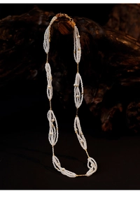 Detail of multi-layer pearl necklace with golden metal accents on a vintage wood base