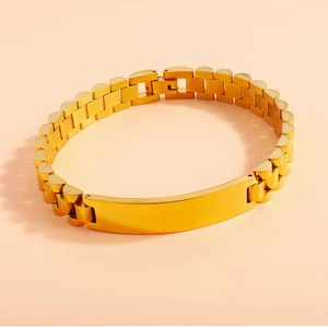 Detailed macro view of a gold watch-band style stainless steel bracelet with blank plate