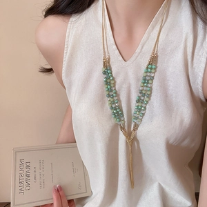 Long beaded layered necklace with golden tassels on a model wearing white top
