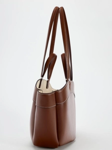 Side view of brown leather tote bag showing dual strap design and premium stitching details
